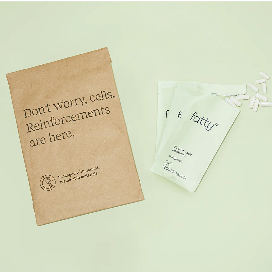 Natural supplement refill pouches with vegan capsules and sustainable packaging on green background.